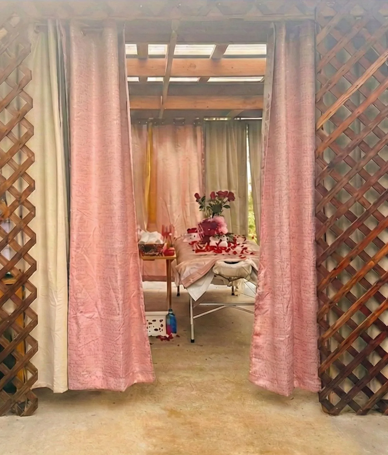 Pink curtains frame an outdoor space with a table set for a party, and floral decorations.