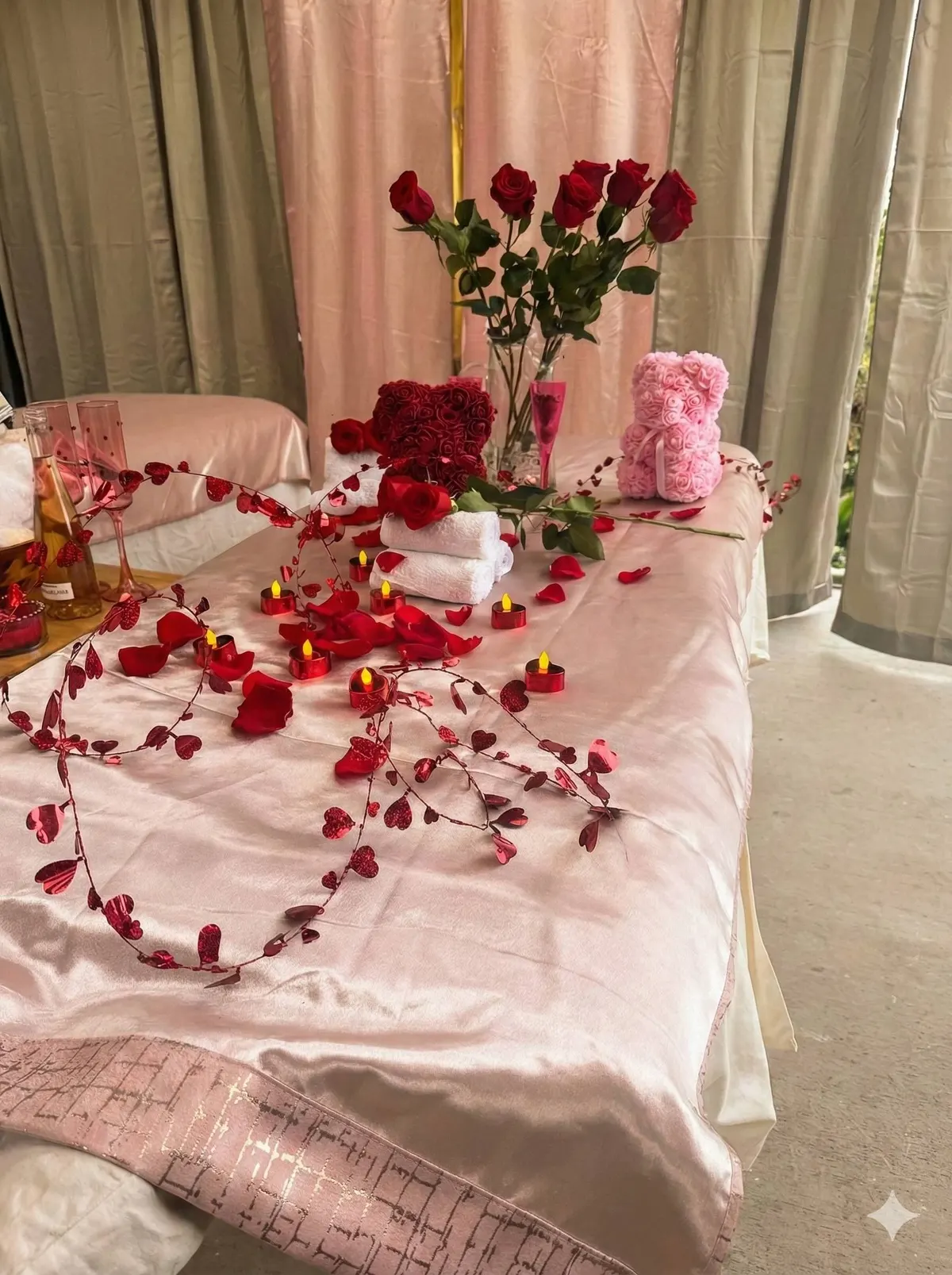 Bed decorated with red roses, petals, and candles for a romantic occasion.