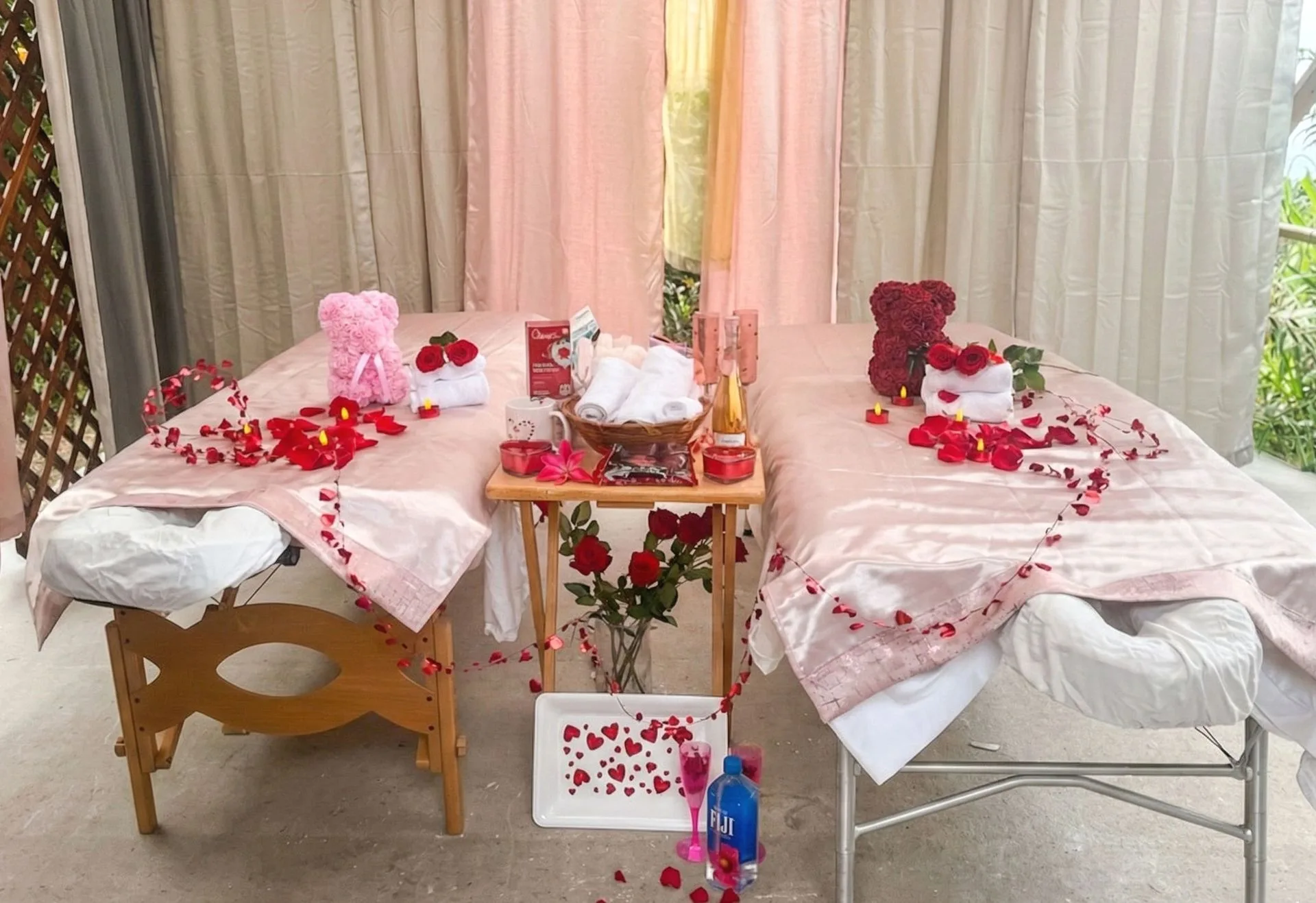 Two massage tables decorated with rose petals, flowers, and gifts, set for a couples massage.